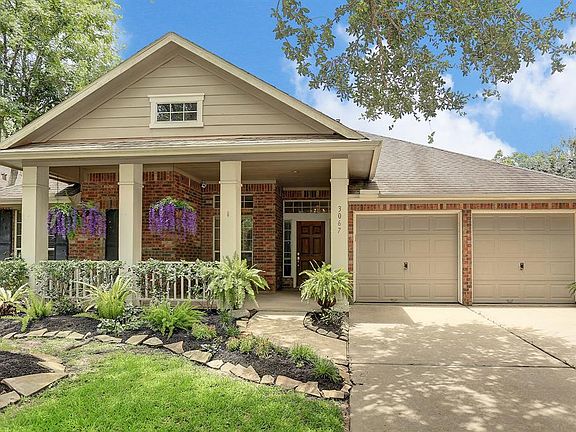 This home has incredible curb appeal with a huge covered front porch, 2-car attached garage with a double wide-driveway, beautiful flower beds, and lots of shade from large trees in the front yard.