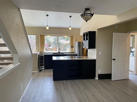 Looking into kitchen from living room with new floors. Only carpet on stairs going to loft.