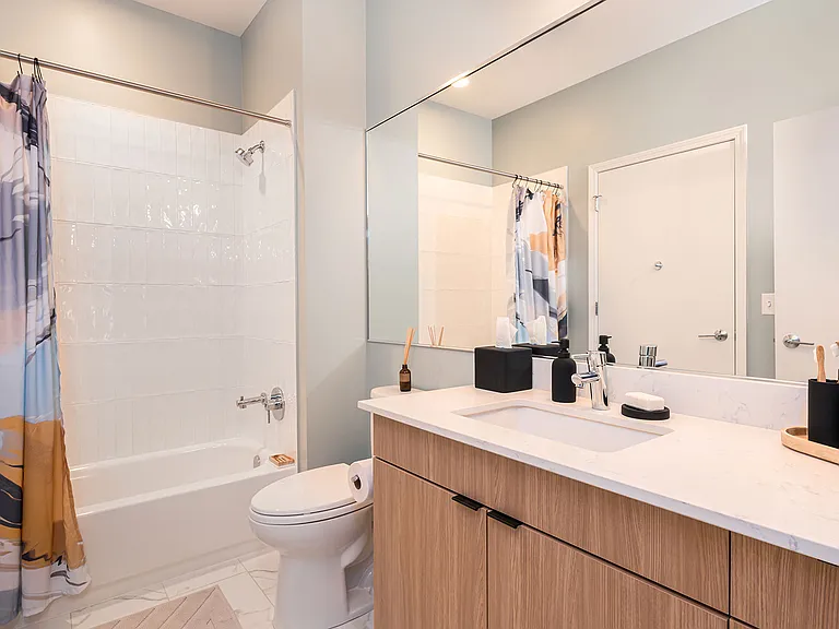 Crisp design meets everyday comfort in this Eleven33 bathroom, featuring quartz countertops, sleek fixtures, and warm wood cabinetry for a calm, modern look.
