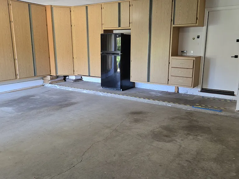Garage with built in storage cabinets and extra fridge.
