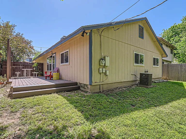 Fully enclosed backyard with new deck, picnic table, and string lights.