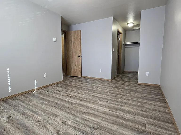 Spacious master bedroom with wood-style flooring, neutral tones, and a bright, airy feel. Enjoy easy access to a walk-in closet and an adjoining second full-size bathroom_designed for comfort and everyday convenience.