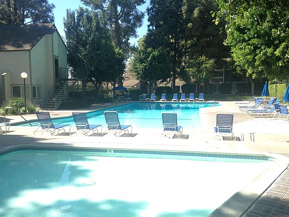 Large lap size pool in background; kids wading pool in foreground. Clubhouse on the left available to rent for parties.