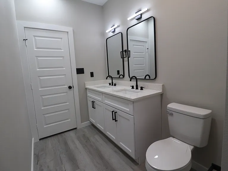 Second full bathroom featuring a spacious double vanity, modern mirrors, sleek black fixtures, and ample storage.