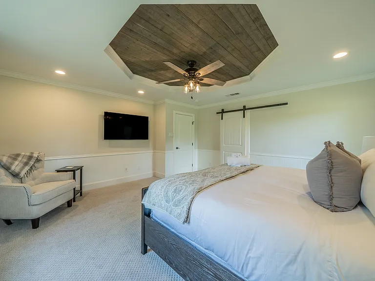 Bedroom 2 Comfort: Large Smart TV, Cozy Armchair & Modern Barn Door Entry