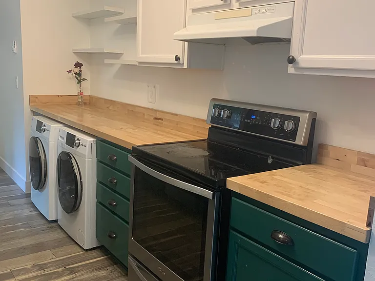 Kitchen with open and closed storage, washer/dryer, stove/oven.