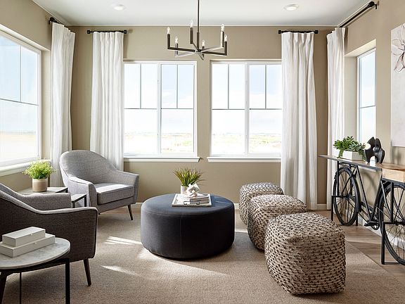 A cozy and inviting living room with large windows, neutral-toned furniture, and decorative accents,