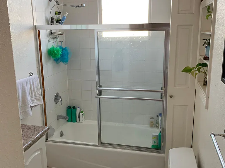 Larger bathroom has shower over full tub, a small closet, and mirrored cabinet over the sink.