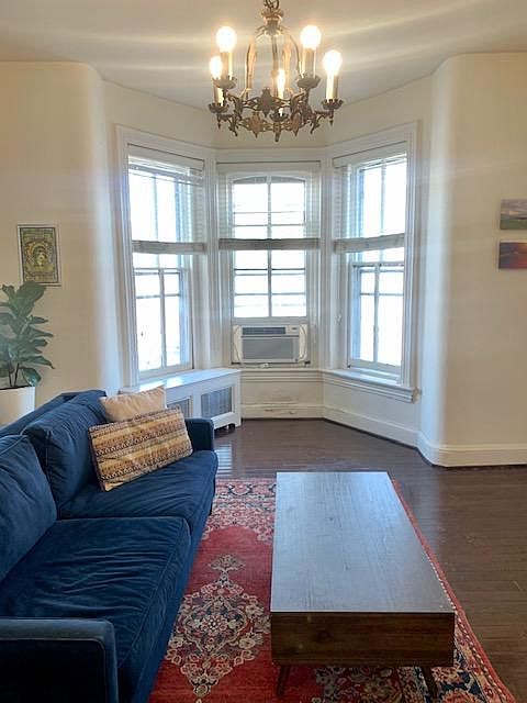 Living Room with couch, chandelier and bay window.