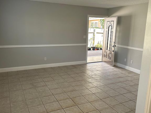 View of living room with front door on the Right as seen from the dining area