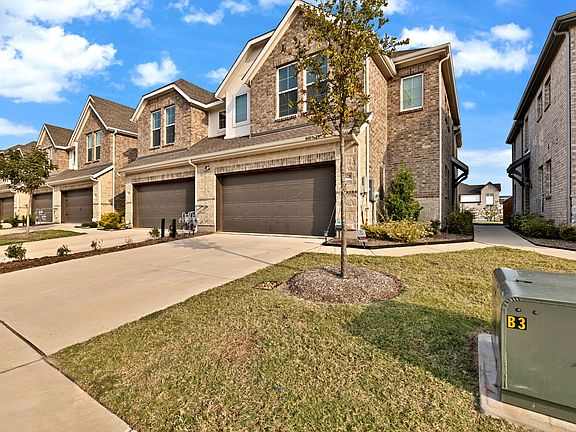 View of front of home with brick and stone siding, driveway, and 2-car garage