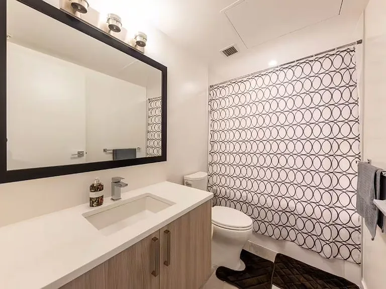 Bathroom featuring wide wall mirrors and a shower room stocked with essential amenities.