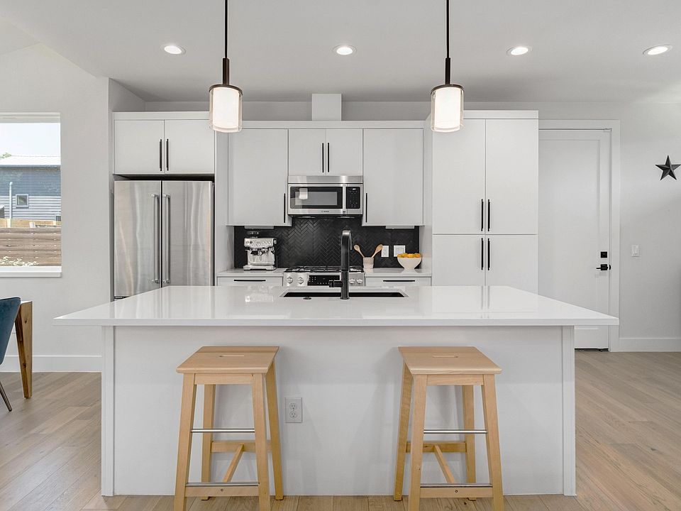 Light and bright kitchen with quartz counters, herringbone backsplash, white cabinetry and plenty of room for extra seating.