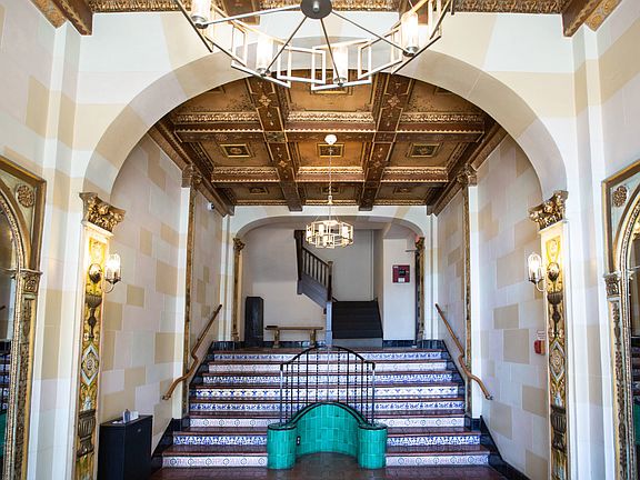 Grand hallway with a high ceiling, a chandelier, and a staircase