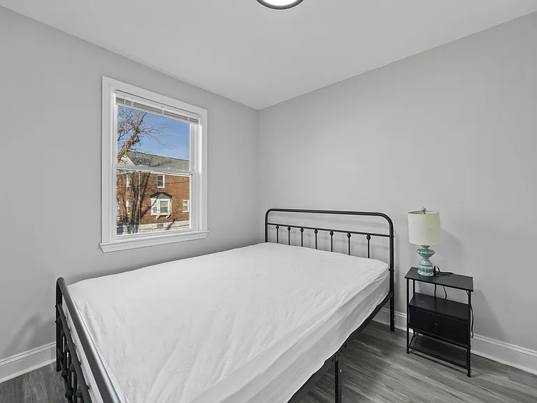 Neat bedroom with a large window, neutral walls, and durable flooring, offering a comfortable layout for a full-size bed.