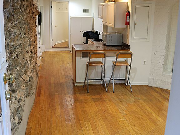 View entering the apartment, living room on right side, kitchenette, followed by separate area and entry to bedroom.