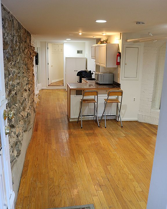 View entering the apartment, living room on right side, kitchenette, followed by separate area and entry to bedroom.
