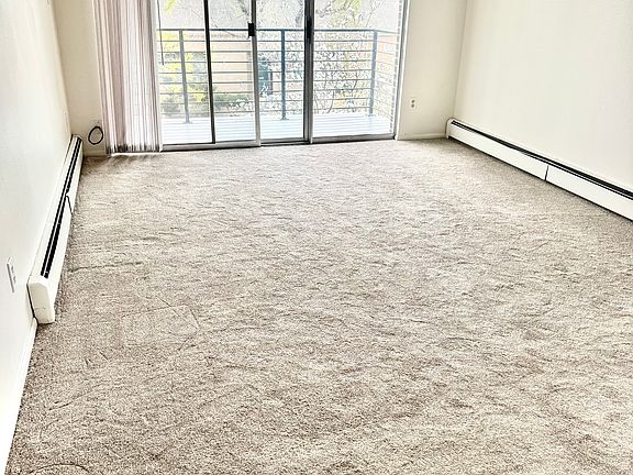 Living room with sliding doors to private balcony. New carpet, economical baseboard heating.