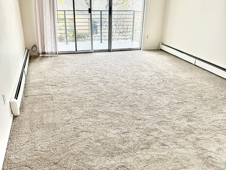 Living room with sliding doors to private balcony. New carpet, economical baseboard heating.
