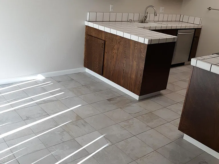 Dining room and part of the kitchen. The lines on the floor are from the sun streaming in through the vertical blinds.