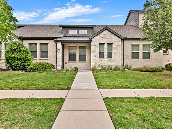 Beautiful townhome featuring brick and stone exterior and a shingled roof.