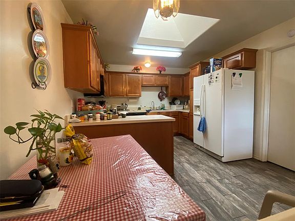 Kitchen with sink, dark hardwood / wood-style flooring, white fridge with ice dispenser, and kitchen peninsula