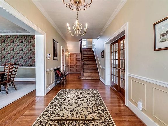 Stunning entry way showcasing gleaming hardwood floors, gorgeous French doors off the living area and beautiful wooden staircase