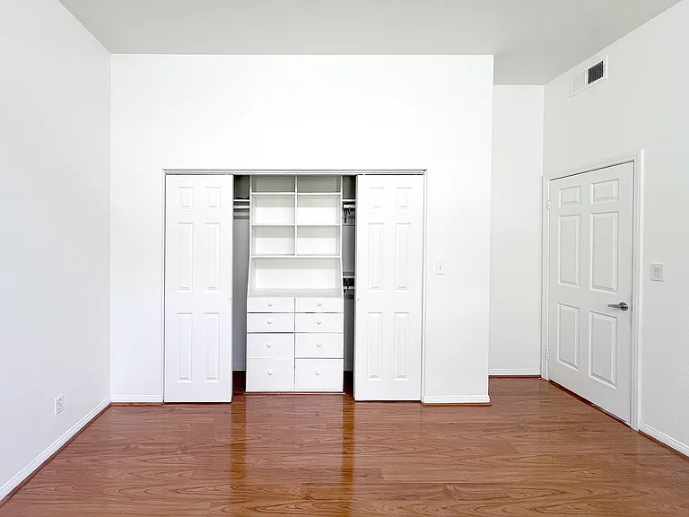 Functional second bedroom featuring custom built-in bookshelves and an integrated closet system.