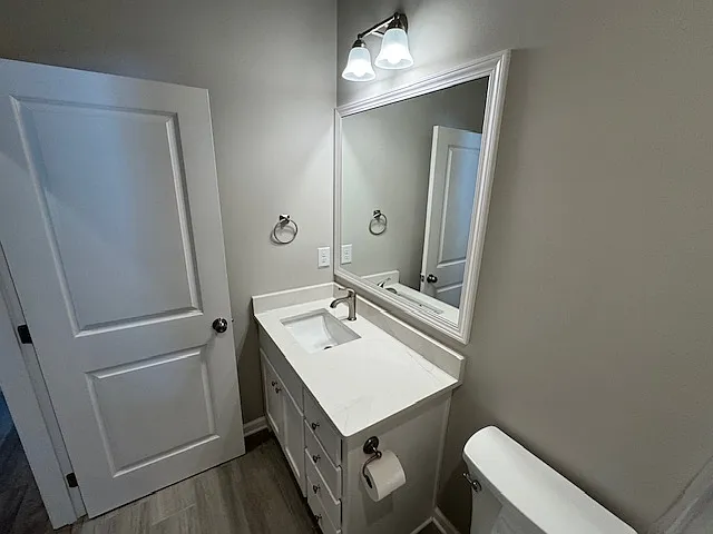 Main level hall bath has ceramic flooring, custom cabinetry with quartz countertop and large mirror.