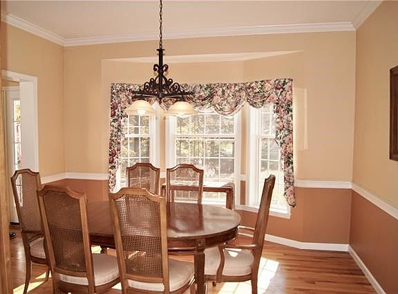 View of dining room with hardwood floors, crown molding and walk-out bay window.