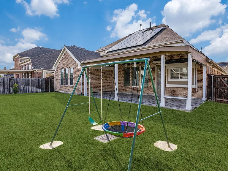 Rear view of house featuring solar panels, a patio area, and a lawn