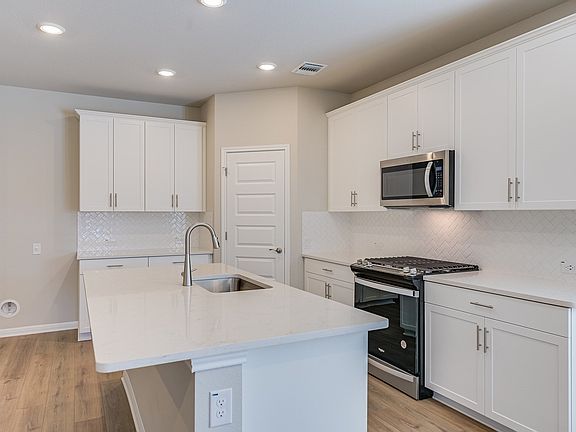 This kitchen features linen-colored cabinets and quartz countertops.