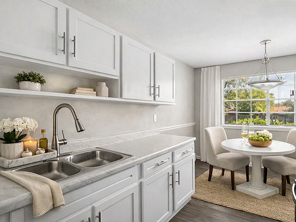 Step into modern living at Courtyards Apartments. This beautifully designed kitchen features sleek white cabinets, stainless steel appliances, and a cozy dining nook, perfect for gatherings. Make your culinary dreams a realityschedule a tour today!
