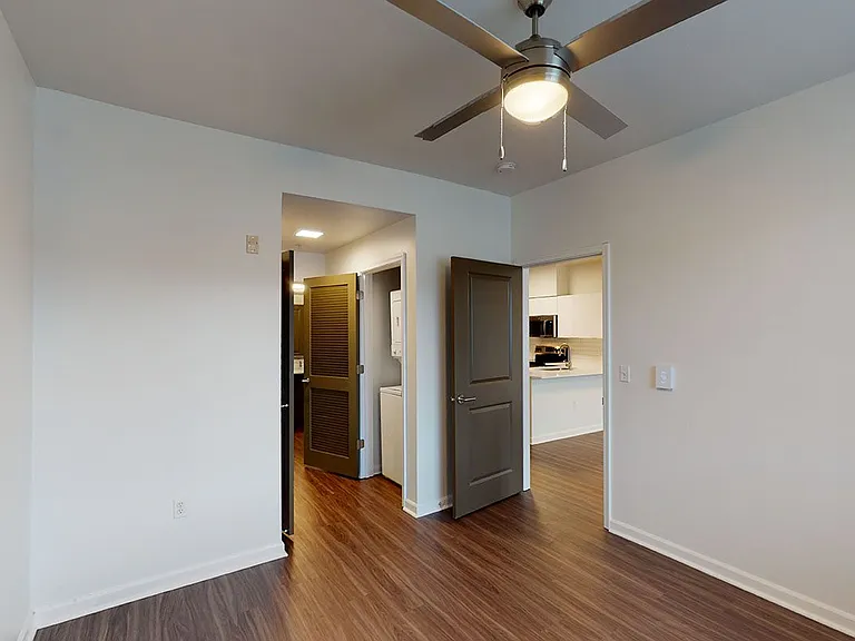 Spacious apartment bedroom with large closet, attached bathroom and wood-style flooring.