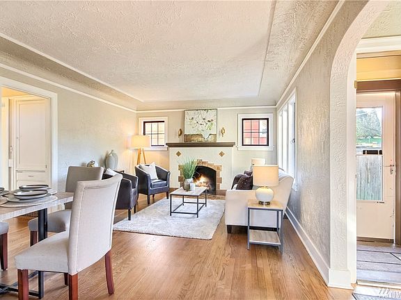 Light-filled living room with wood burning fireplace, coved ceiling and beautiful hardwood flooring.
