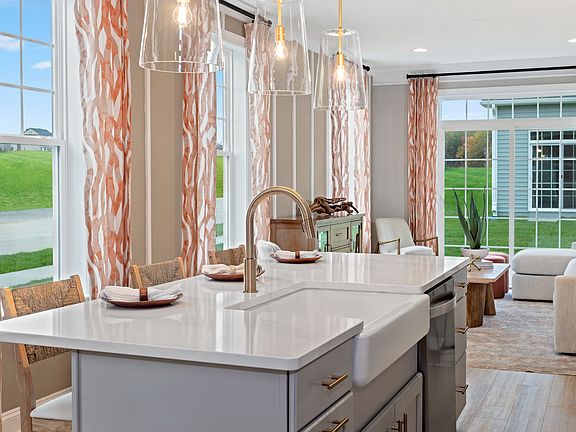 Stunning bright and light kitchen with windows, gray lower cabinets and white counters, and stainles