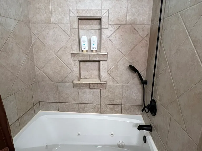 Jacuzzi tub with rain-head and handheld shower. Beautiful tile with double shower niche. Large tub-side seating for shaving legs or using for tablet, laptop or cell phone.