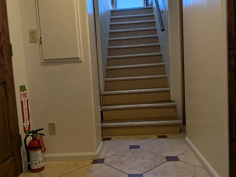 Stairs to Garden Level, the location of a private Suite (bedroom, private bath, gas fireplace, heated bathroom tiles, closets, refrigerator and its own washer dryer. Access the laundry room, bonus rooms and 1 car garage