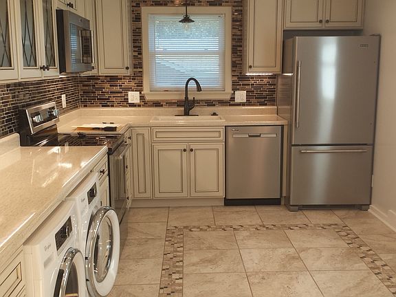 Custom design tile floor, glass tile backsplash, detailed cabinet doors, undercounter w/d
