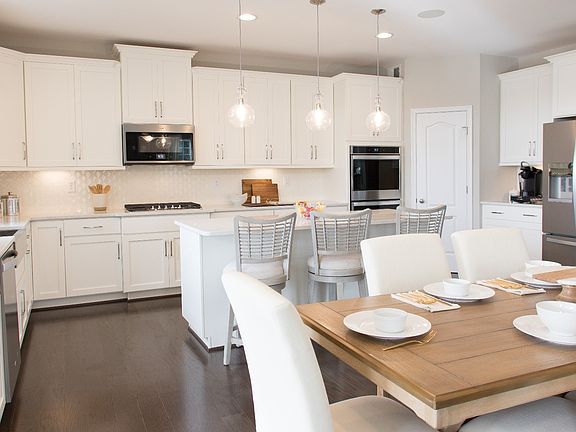 Island kitchen with white cabinets and stainless appliances in a DRB Homes Cypress II home plan at H