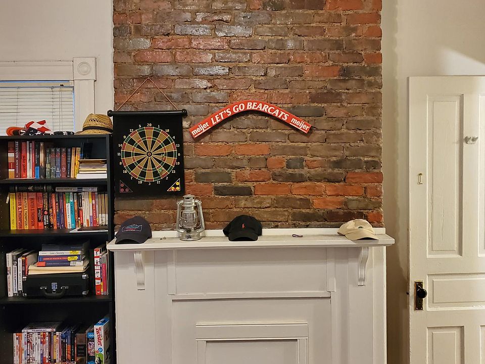 Living room with fireplace, exposed brick, and hardwood floors