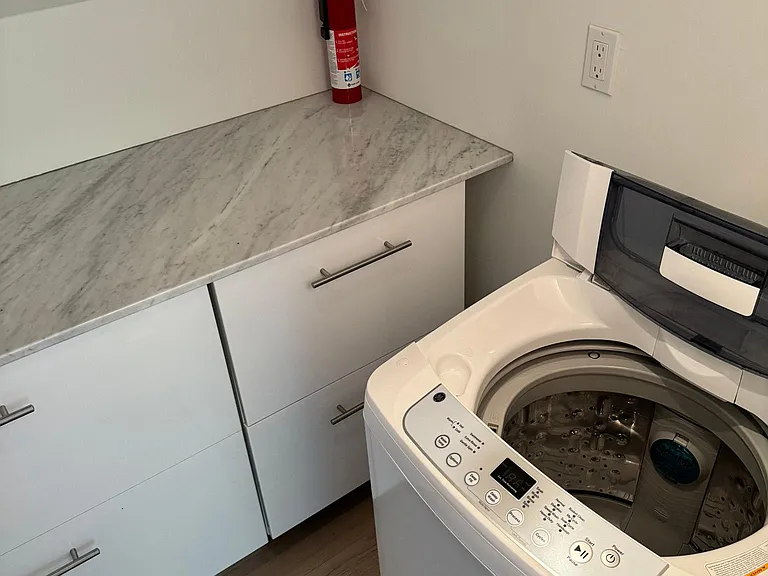 Laundry room with washer, storage cabinets and laundry rack