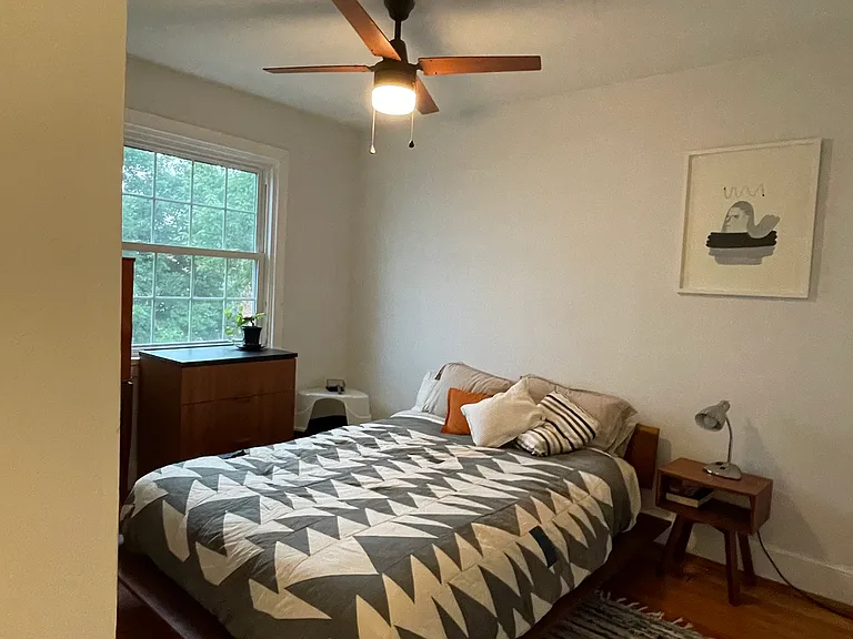 Bedroom 2 with original heart pine floors, modern ceiling fan, and fresh paint.