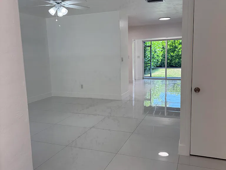 View from the entrance of the home, seeing the open floor plan and the double wide sliding glass door out to the screened-in back porch and private, landscaped backyard.