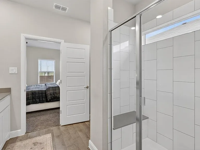Spacious bathroom featuring a glass-enclosed shower with white tiled walls and an integrated bench