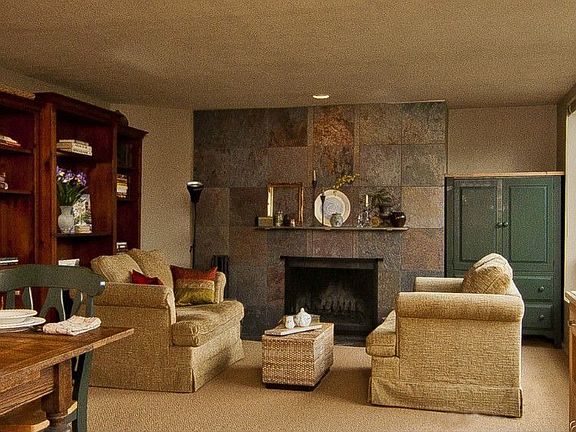 Soft earth tones and a wood burning fireplace surrounded by slate tiles create a warm, comfortable ambience.