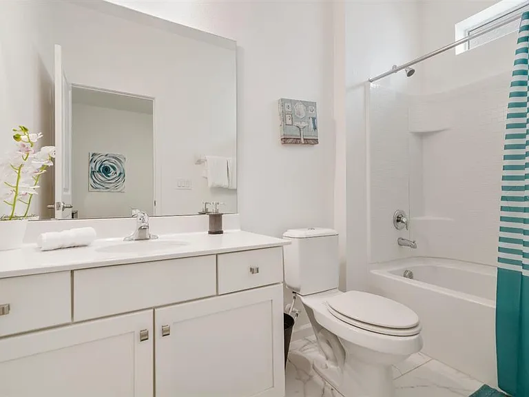 Bathroom features a wide vanity with large mirror, ample counter space, and a shower/tub combo with tile surround.