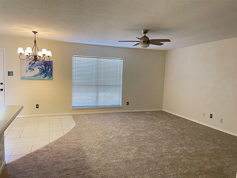 Carpeted empty room with ceiling fan with notable chandelier