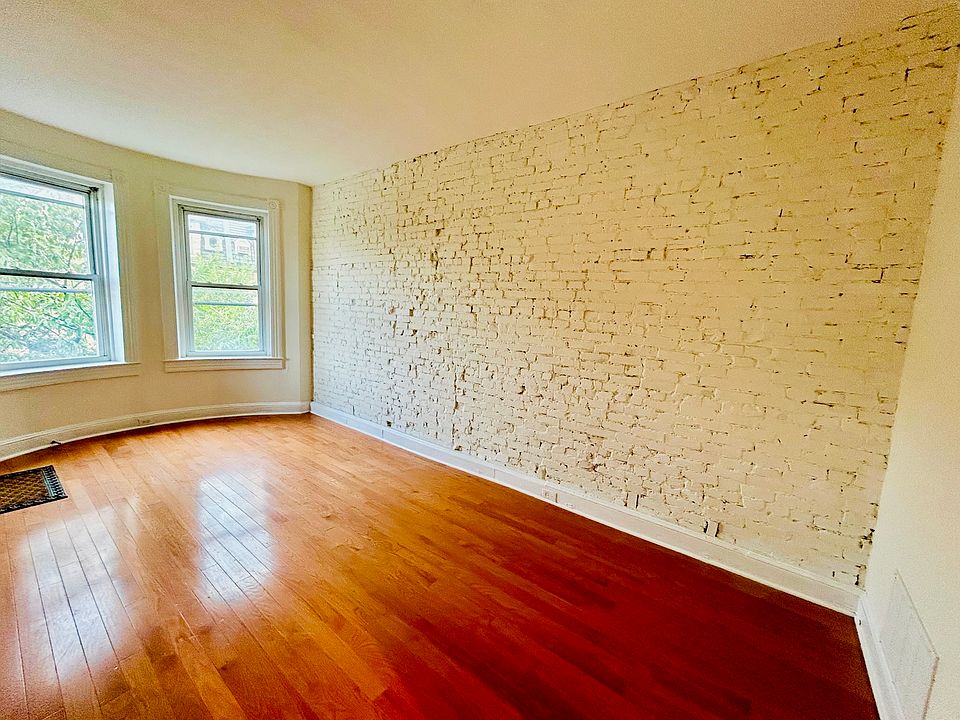Welcome home! Living room has exposed brick walls and gleaming refinished hardwood floors.