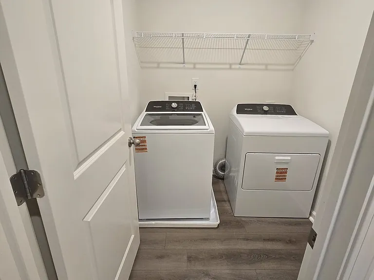 View of the laundry room, washer and dryer and a shelf.